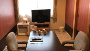 A hotel room with a flat-screen TV, a small table, two armchairs, a coffee maker, and a remote control on the table. - Hotel Arima Koukaen (Nishinomiya)