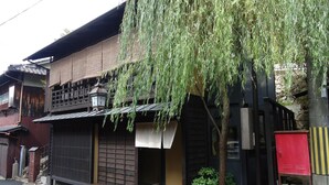 A traditional Japanese building with a sliding door, a small garden, and a red storage box. - Hotel Arima Koukaen (Nishinomiya)