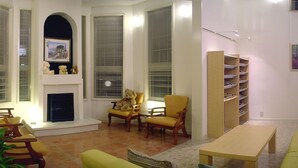 A living room with a fireplace, two armchairs, a coffee table, and a bookshelf.