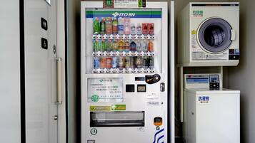 A vending machine with a variety of drinks and a small refrigerator below it.