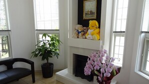 A living room with a fireplace, a potted plant, and a shelf with stuffed animals. - Family Lodge Hatagoya Chichibu (Chichibu)