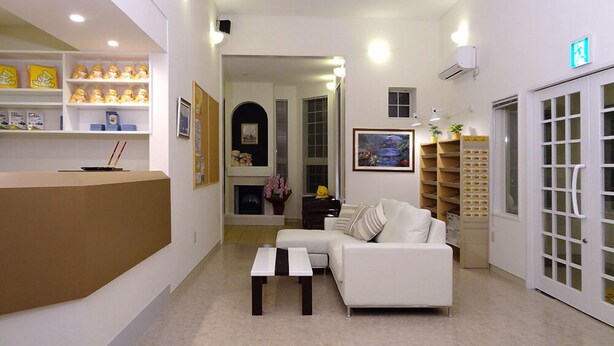 A reception area with a reception desk, a white sofa, and a coffee table. There are shelves with various items and a painting on the wall. - Family Lodge Hatagoya Chichibu (Chichibu)