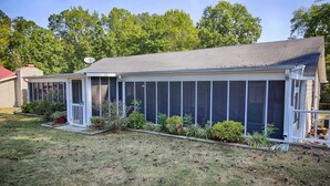 Une maison de plain-pied dotée d’un patio couvert, d’un garage et d’une pelouse agrémentée de différents arbustes.