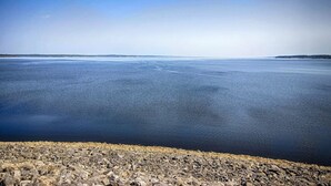 Une étendue d’eau large et paisible, bordée d’une côte rocheuse.
