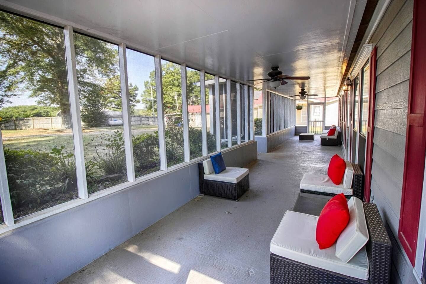 A covered porch with seating, large windows, and a ceiling fan.