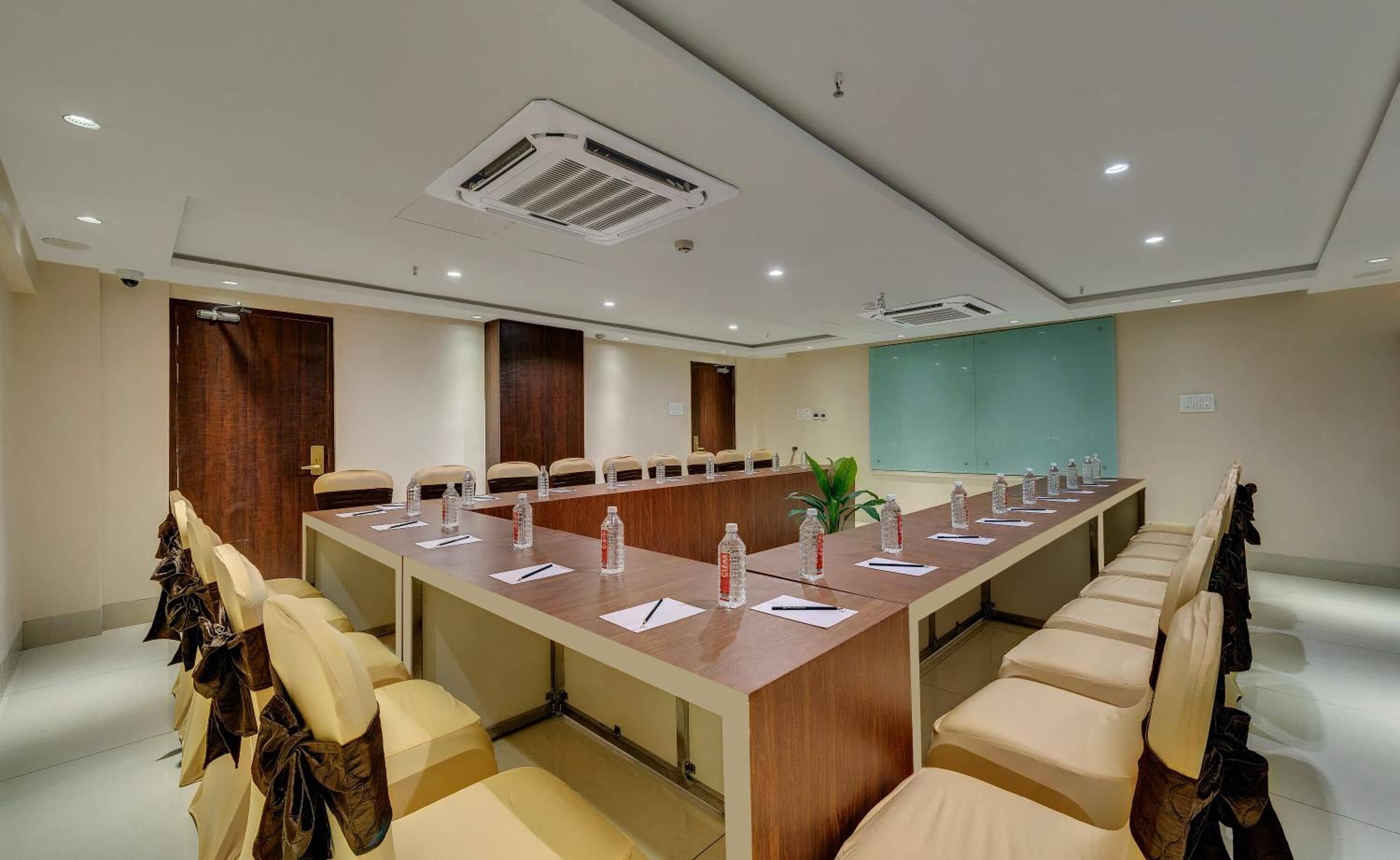 A conference room with a long table, chairs, and a large screen.