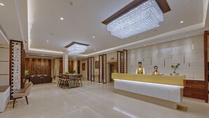 Un moderno vestíbulo de hotel con mostrador de recepción, zona de estar y detalles decorativos.