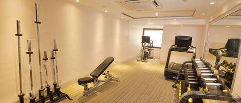 A gym with exercise equipment, a bench, and a treadmill.