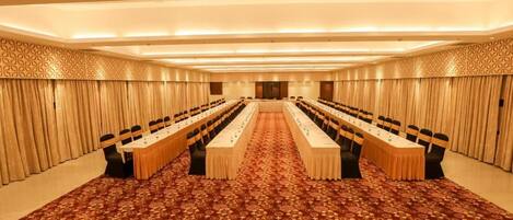 A conference room with a long table, chairs, and a patterned carpet.