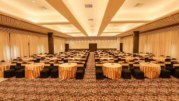 A large conference room with rows of tables and chairs, a patterned carpet, and a high ceiling with recessed lighting.