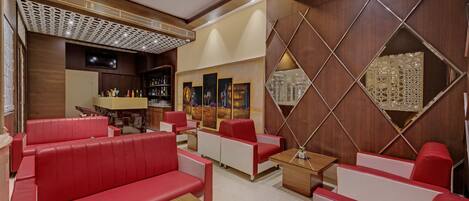 Ein moderner Lounge-Bereich mit roter und weißer Sitzgelegenheit, einem Holztisch und einer dekorativen Wandverkleidung.