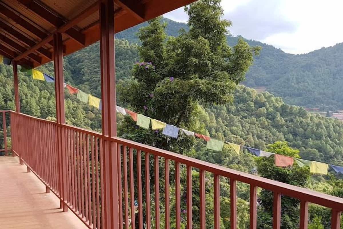 Ein Holzbalkon mit Metallgeländer, der auf eine gebirgige Landschaft blickt.