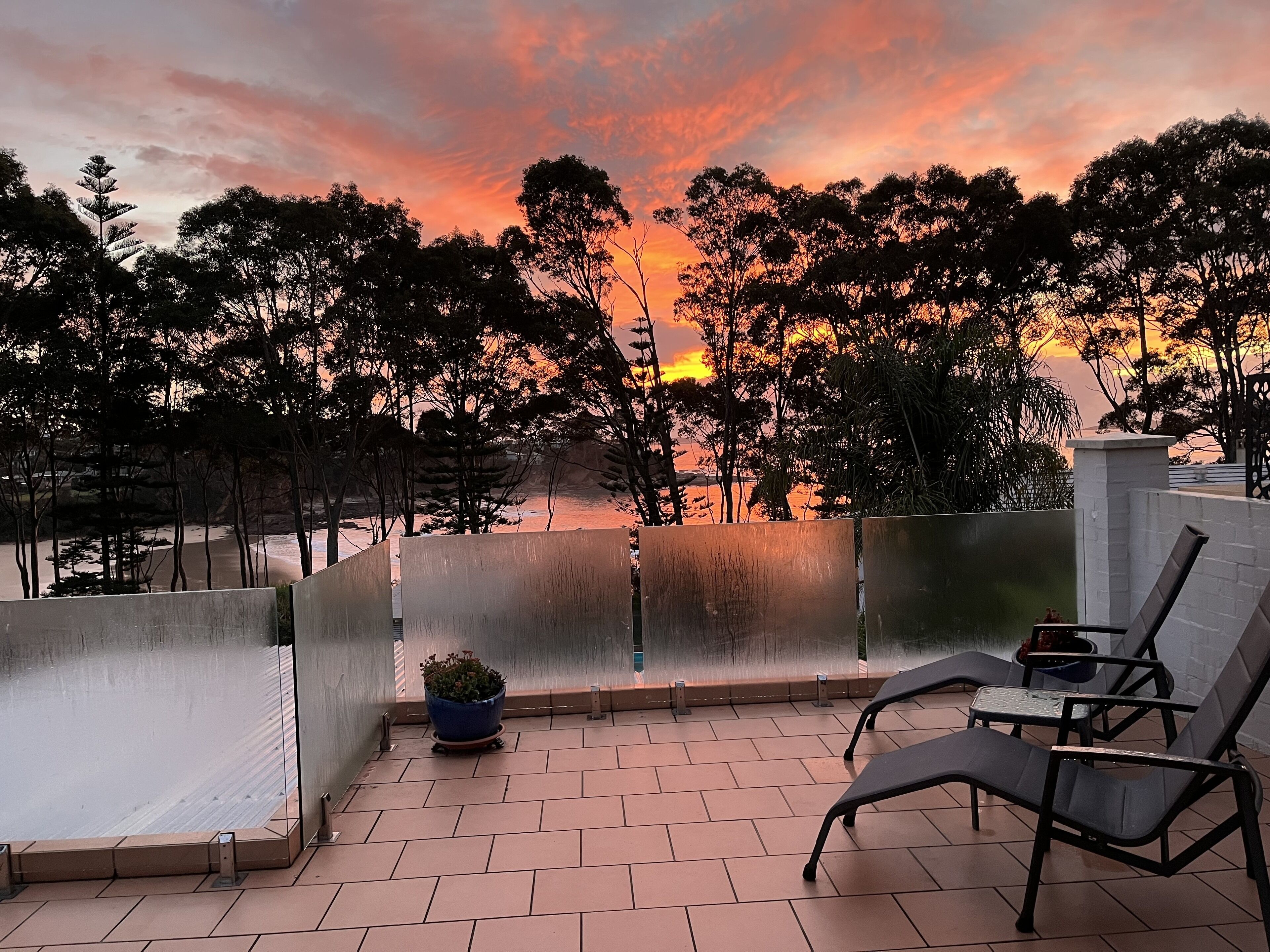 Une terrasse avec vue sur les arbres et un coucher de soleil.