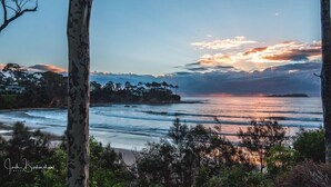 Un paisaje costero con playa, olas del océano y una puesta de sol.