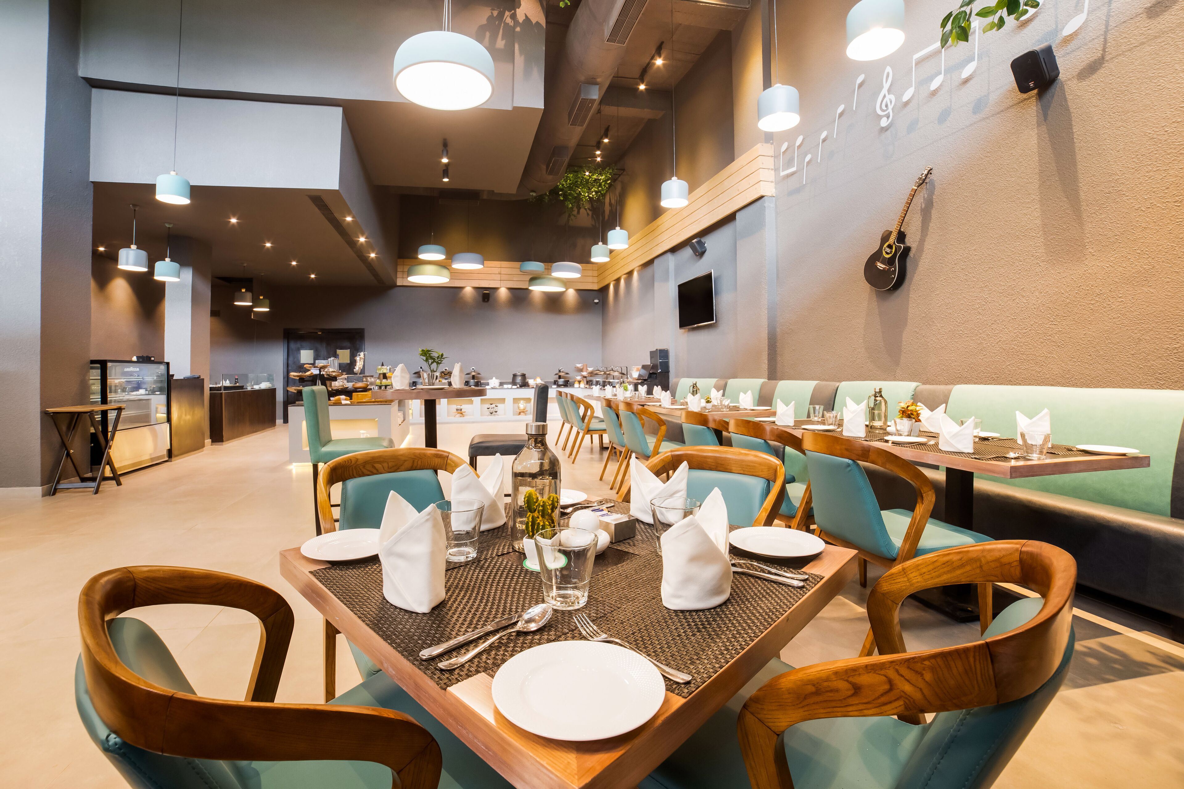 A restaurant with wooden tables, teal chairs, and a modern interior design.