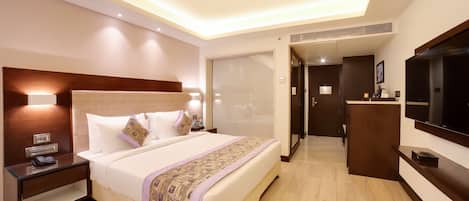 Una habitación de hotel con una cama grande, mesitas de noche, un televisor y una zona de escritorio.