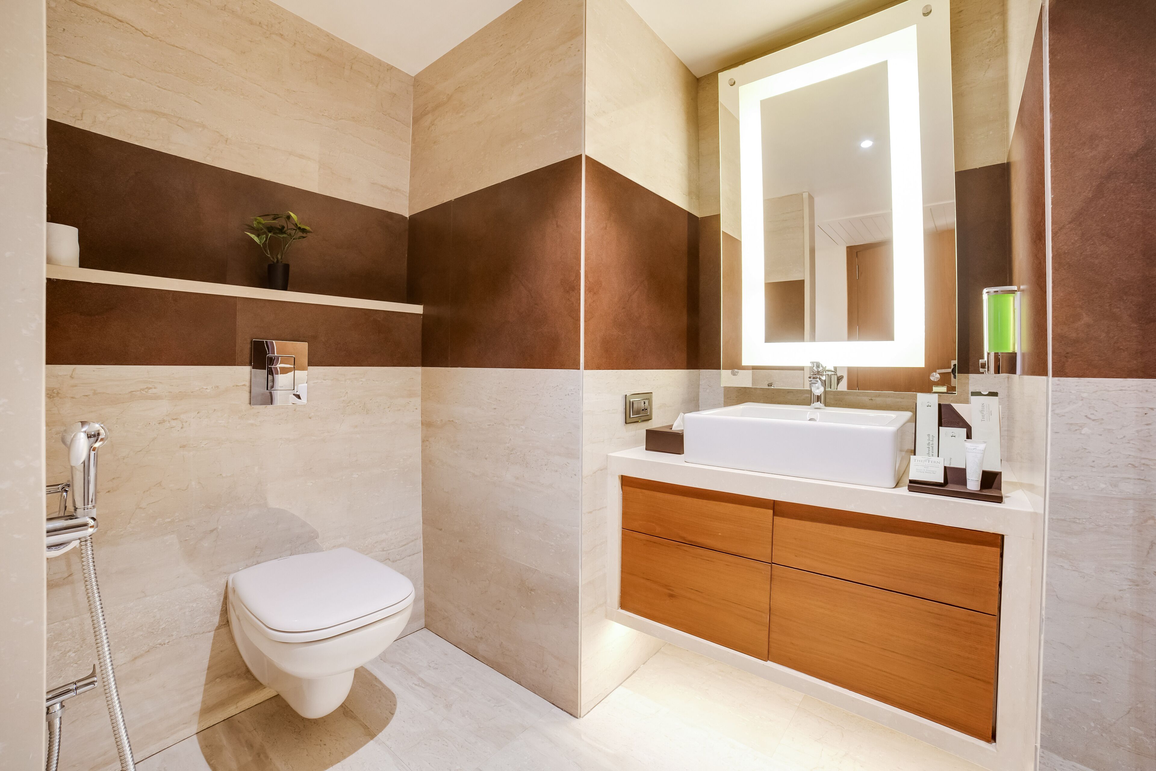 Egy modern fürőszoba, amelyben WC, zuhanyzó és mosdókagyló található, a mosdókagyló felett pedig tükör van.