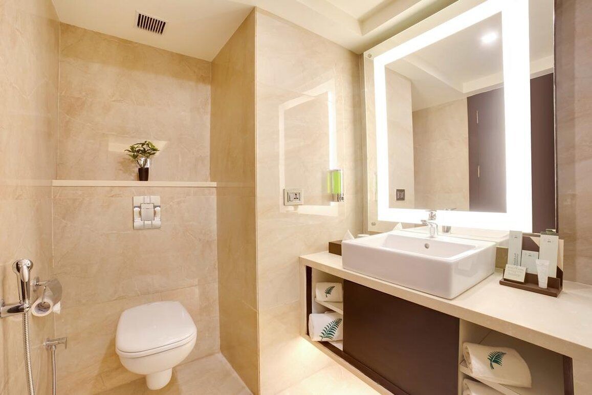 A modern bathroom with a white sink, large mirror, and a toilet.