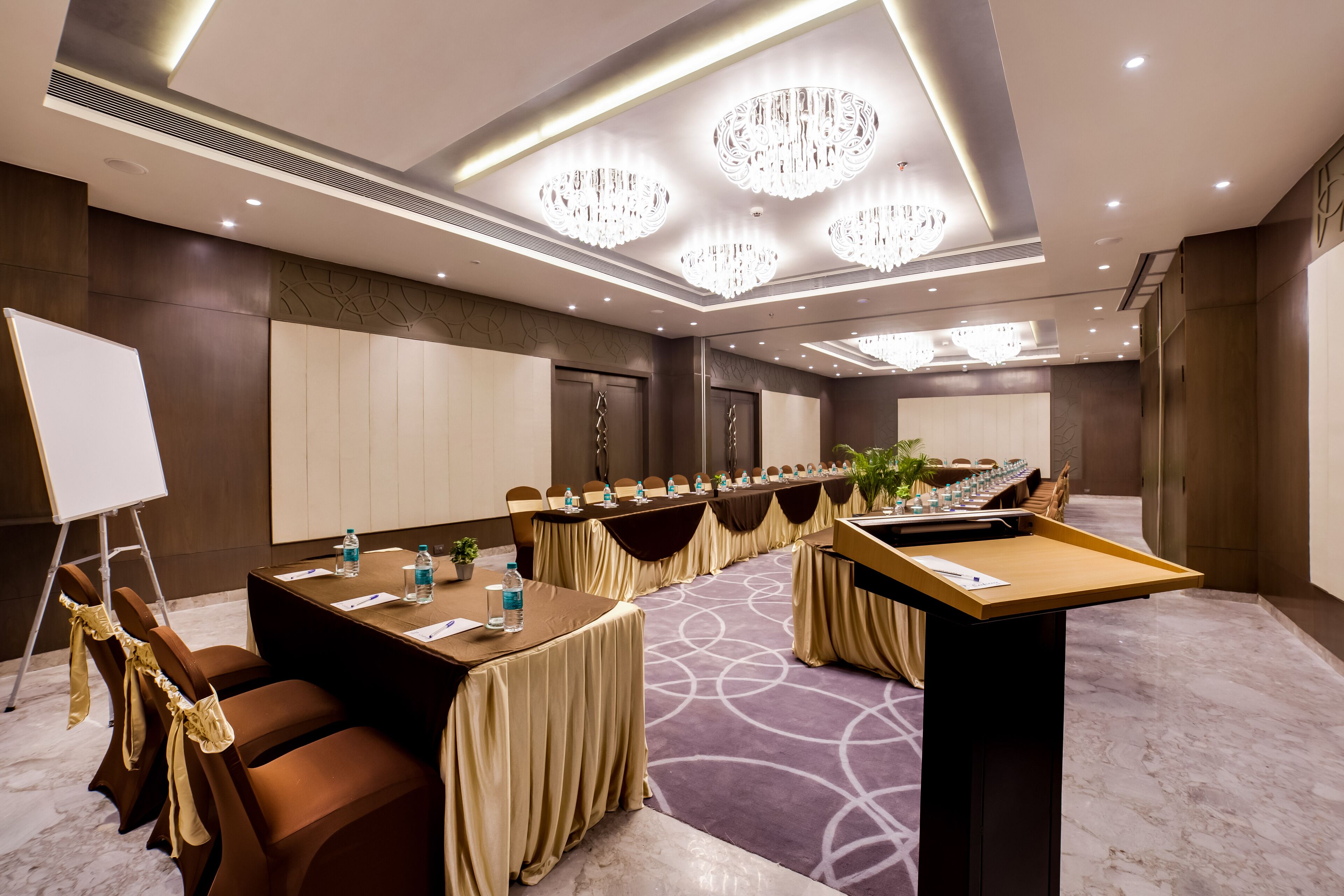 A conference room with a long table, chairs, a podium, and a whiteboard.
