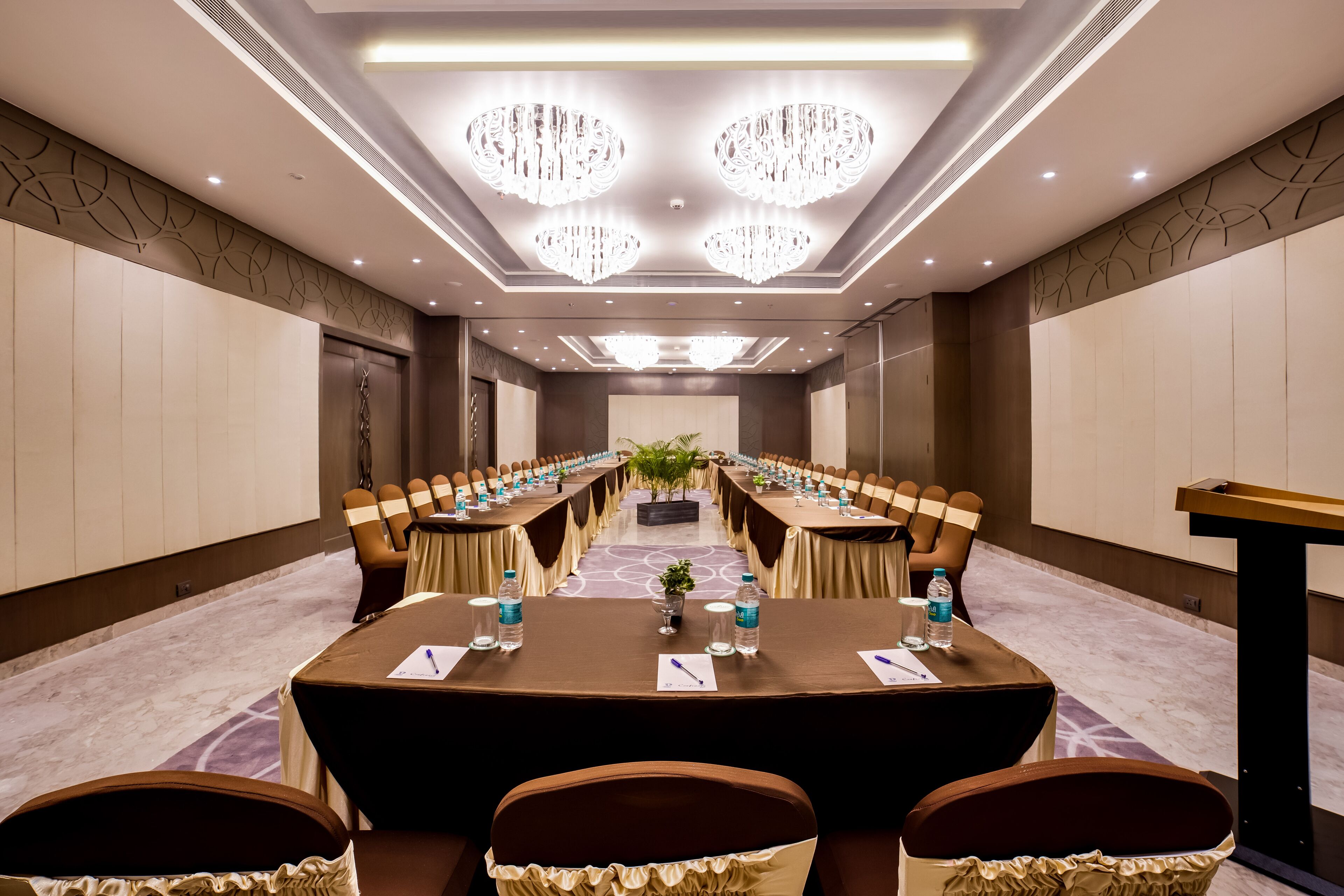 A conference room with a long table, chairs, water bottles, and a podium.