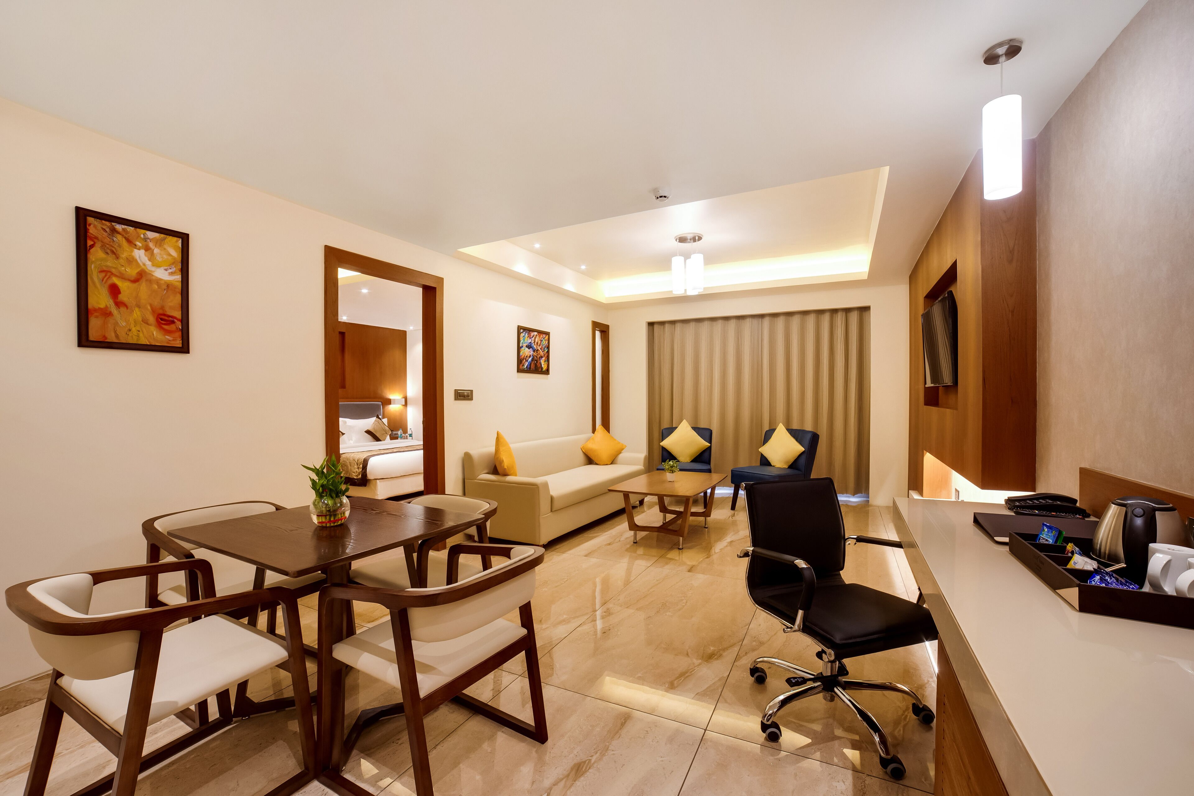 A hotel room with a dining area, a sofa, a desk, and a chair.