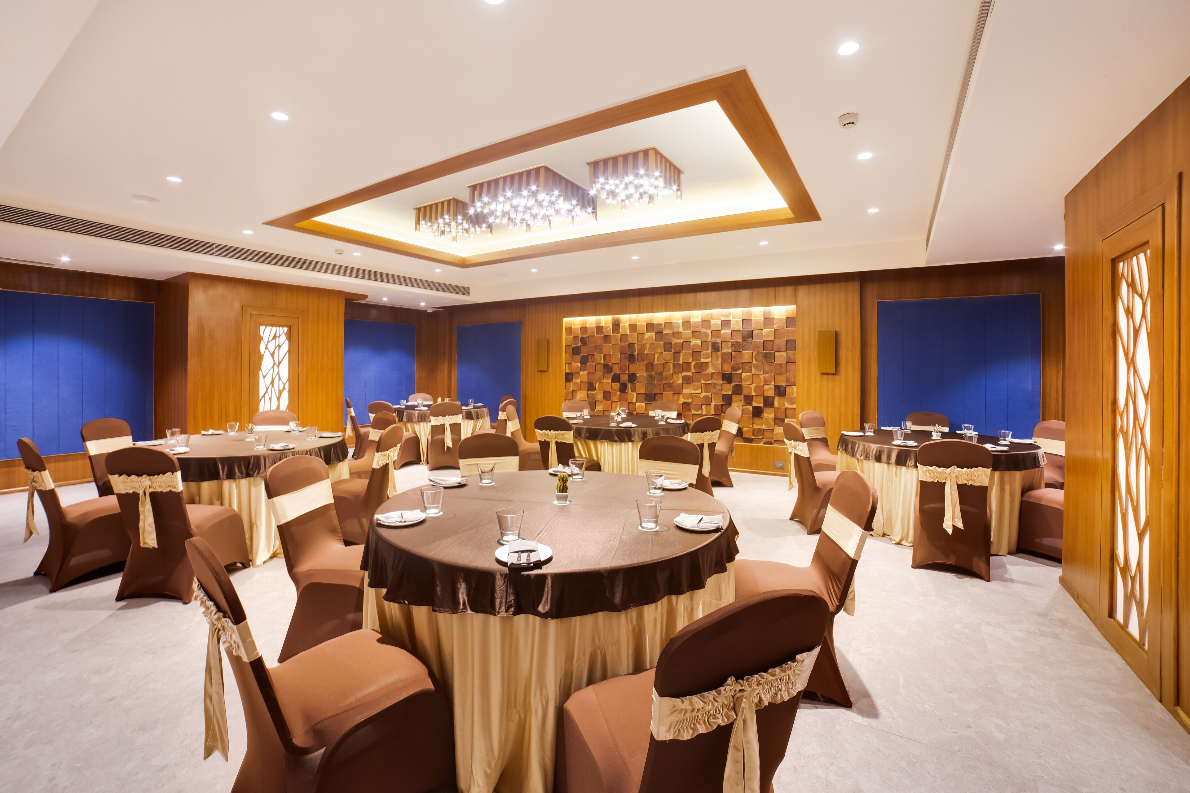 A conference room with round tables, brown chairs, and a decorative ceiling.