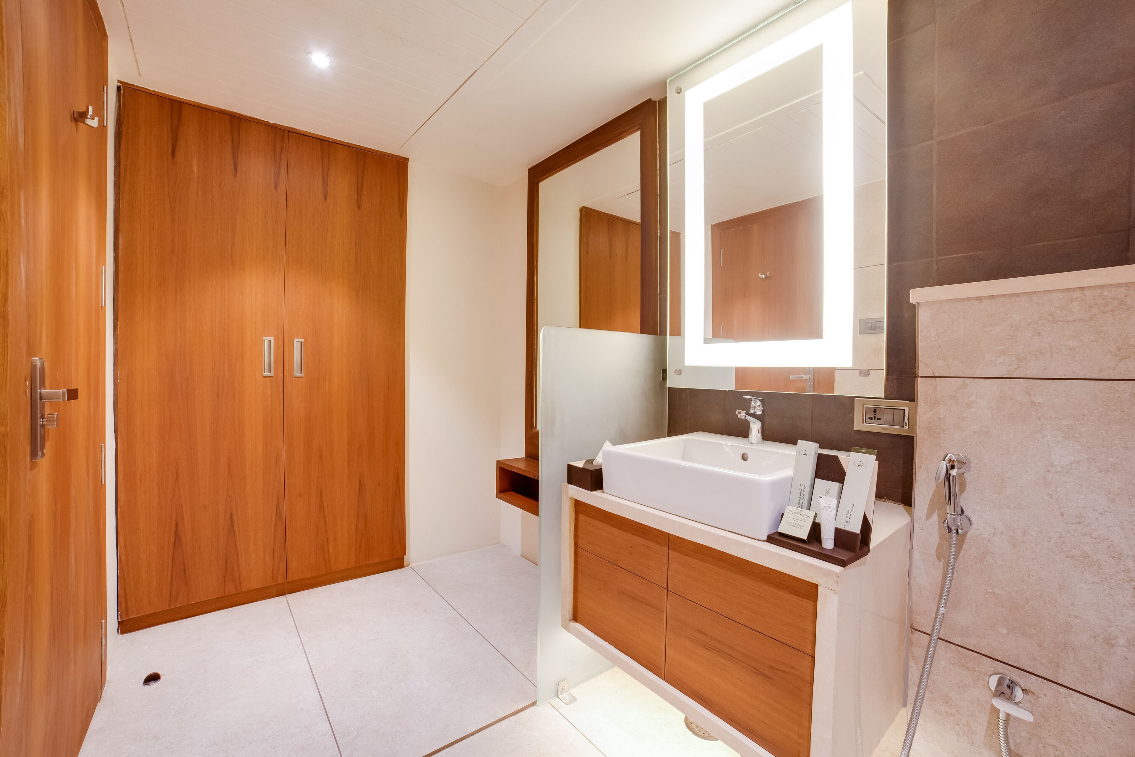 Un baño moderno con un armario de madera, un espejo grande, un lavabo blanco y una ducha.