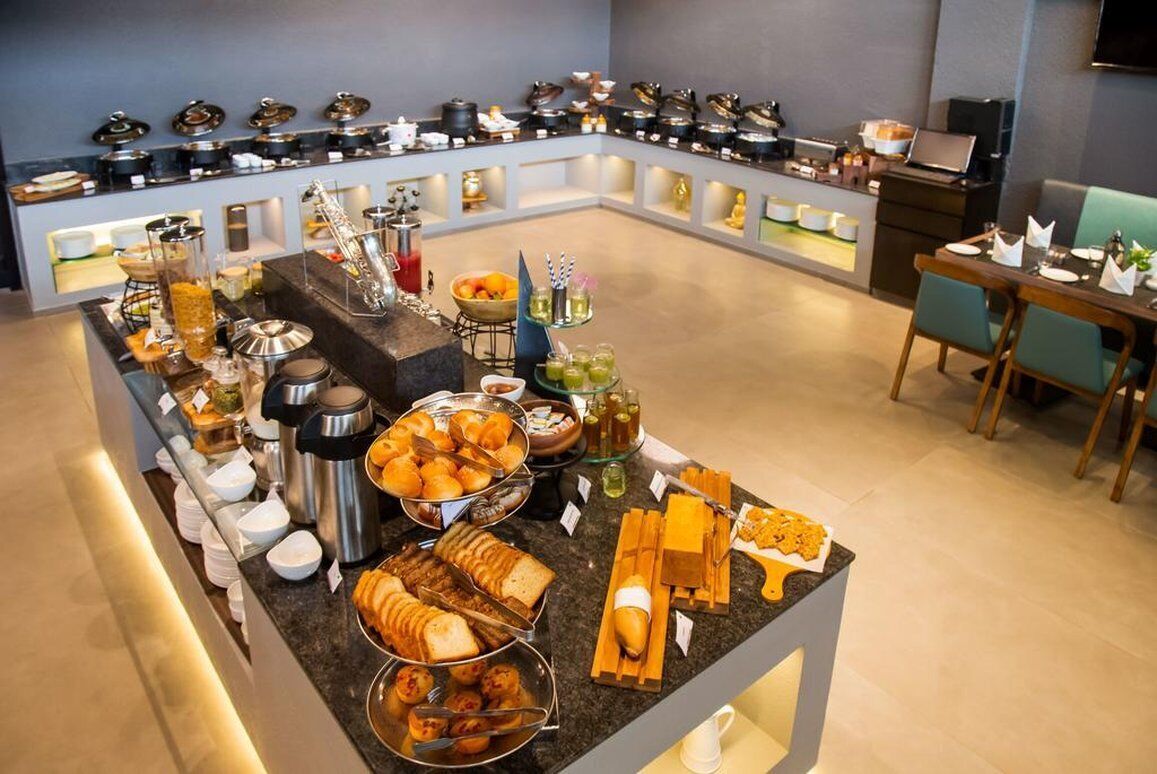 A buffet setup with various food items and beverages, a seating area with tables and chairs, and a kitchen area in the background.