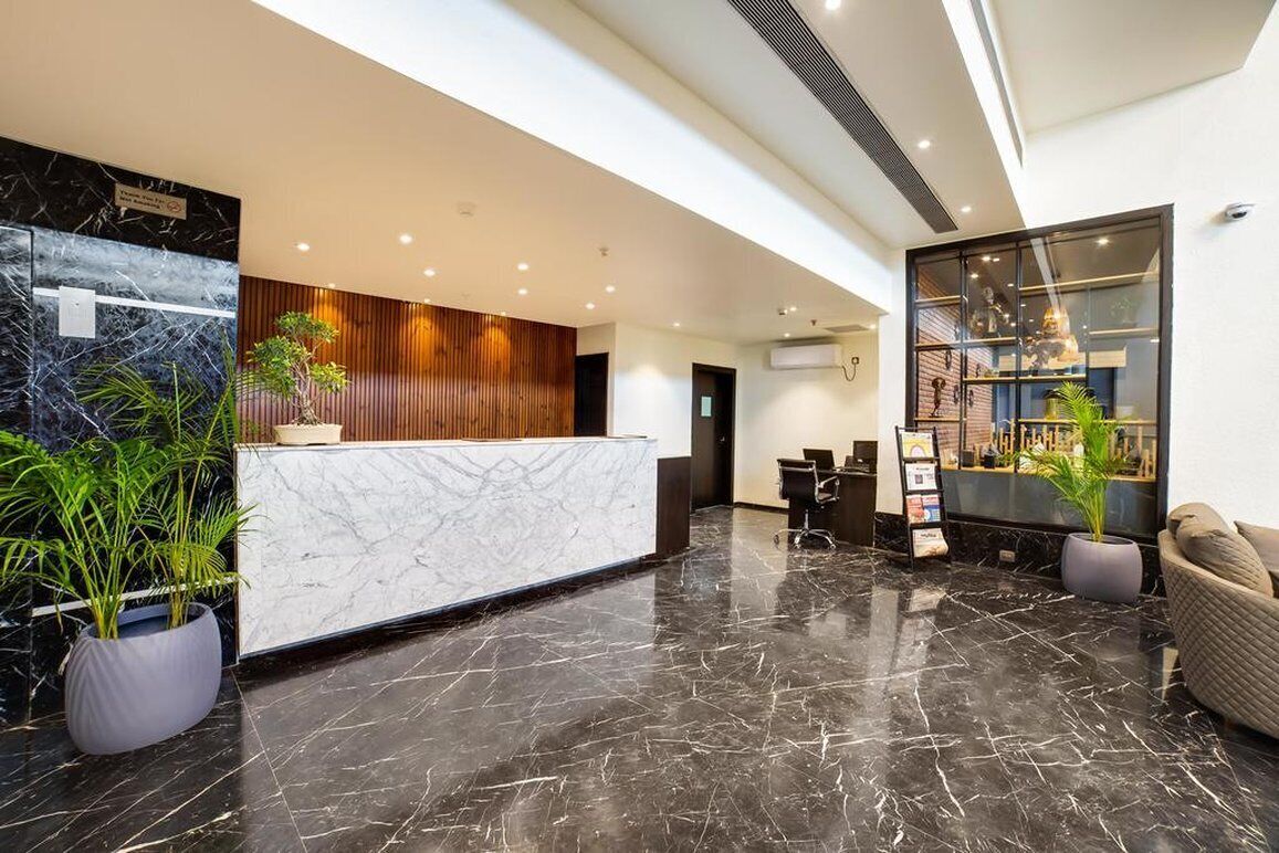 A modern reception area with a marble counter, wooden paneling, and potted plants.
