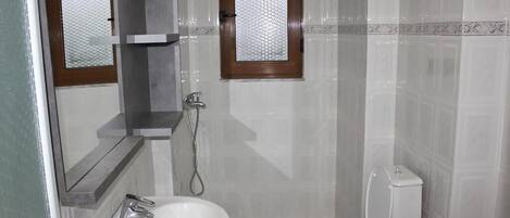 A bathroom with a white sink, a toilet, a mirror, and a window.
