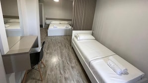 Quarto de hotel com uma cama, uma escrivaninha e uma cadeira.