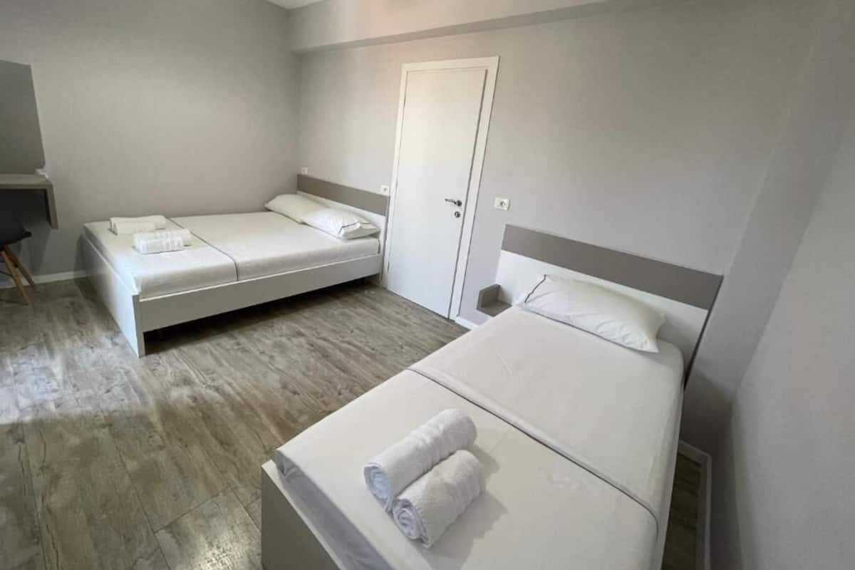 A hotel room with two single beds, a desk, and a door.