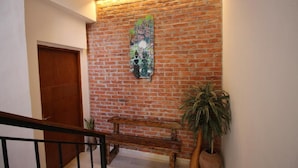 Uma escadaria com parede de tijolos, um banco de madeira e plantas em vasos.