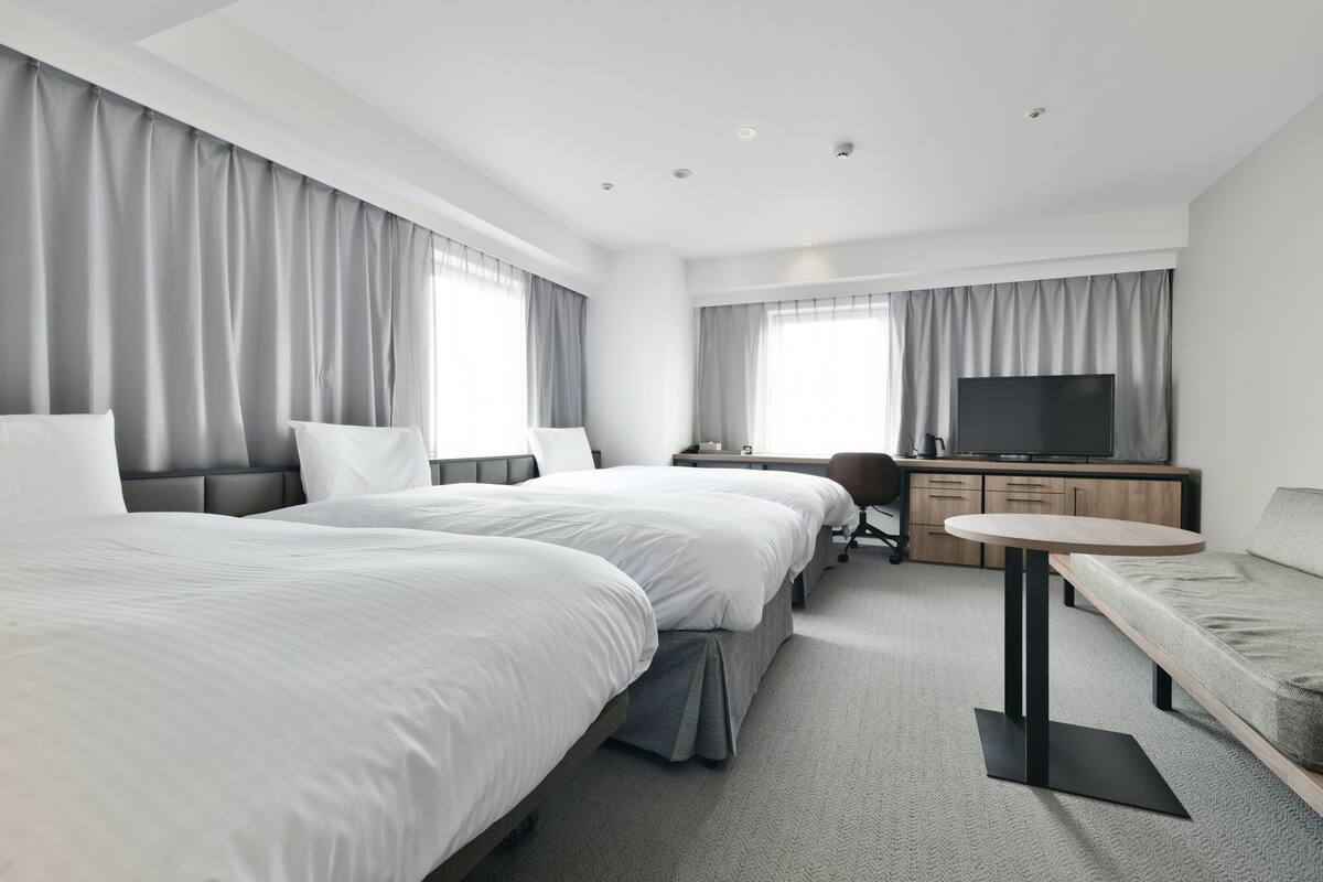 Een moderne hotelkamer met twee grote bedden, een bureau, een televisie en een bank.