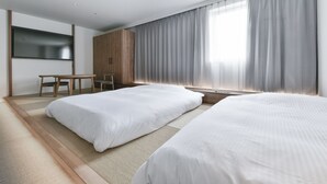 Une chambre d’hôtel moderne équipée de deux lits, d’un bureau et d’une télévision.