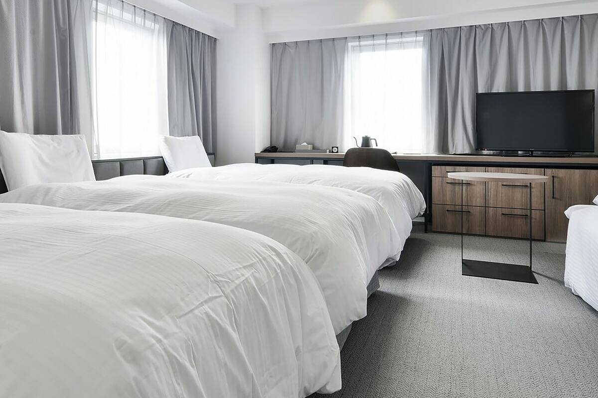 Een moderne hotelkamer met twee bedden, een bureau, een flatscreen-tv en een klein kitchenette.