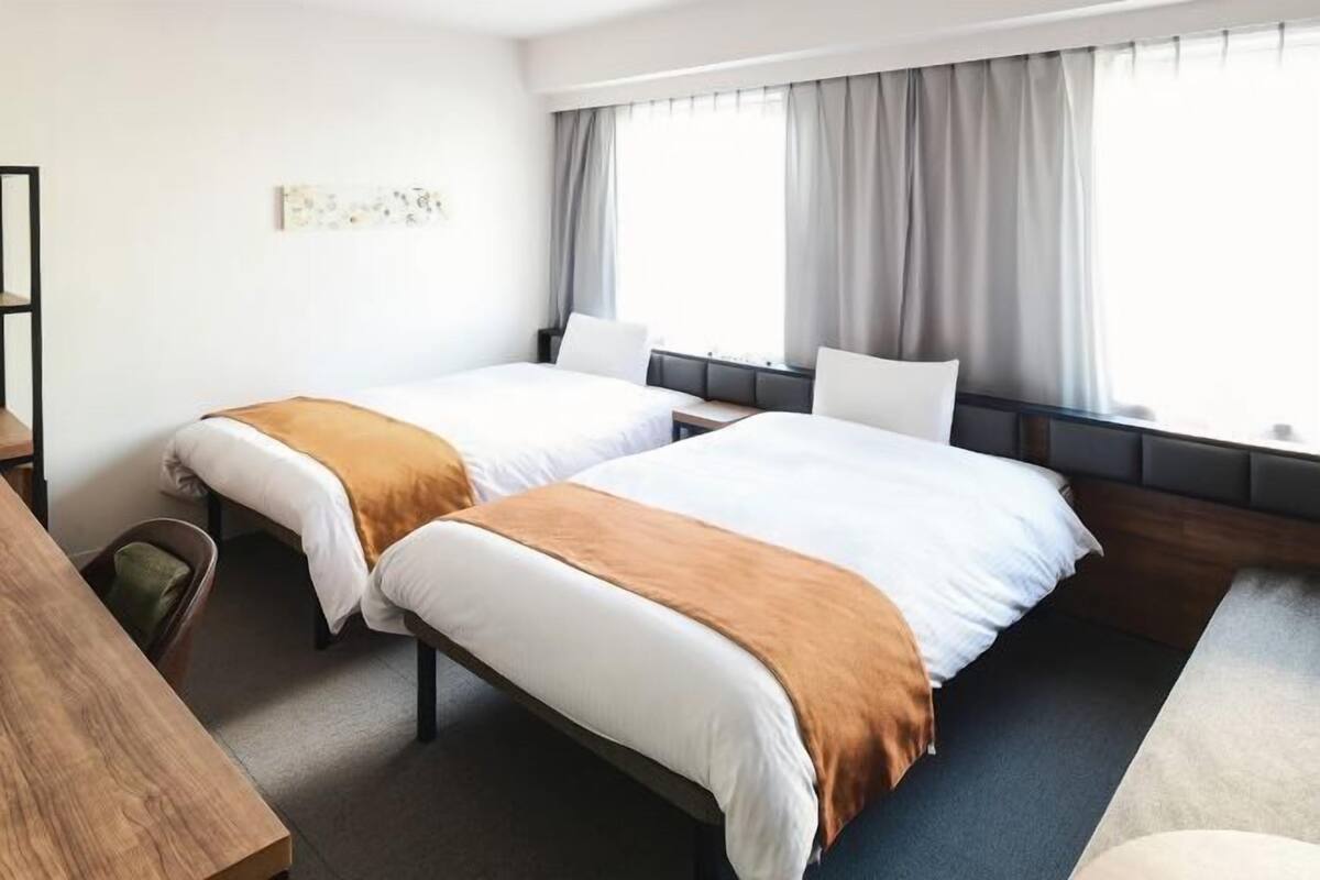 Een hotelkamer met twee bedden, een bureau en een stoel.