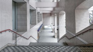 Un intérieur moderne avec des murs carrelés, un sol à carreaux et un escalier doté de rampes rouges.