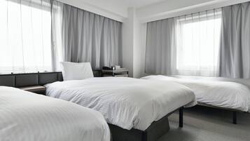Habitación de hotel con dos camas, una mesita de noche y una ventana con cortinas.