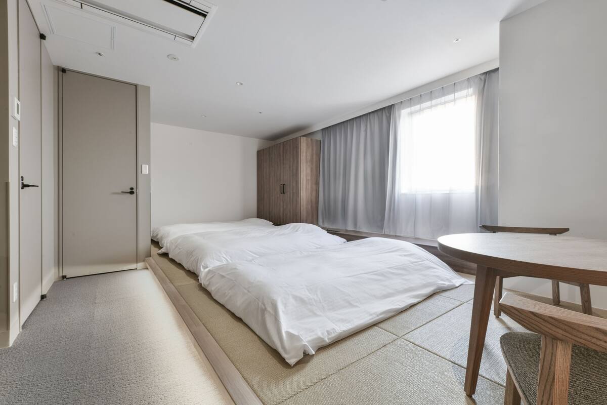 Een moderne hotelkamer met een bed, een klein houten tafeltje en een raam met gordijnen.