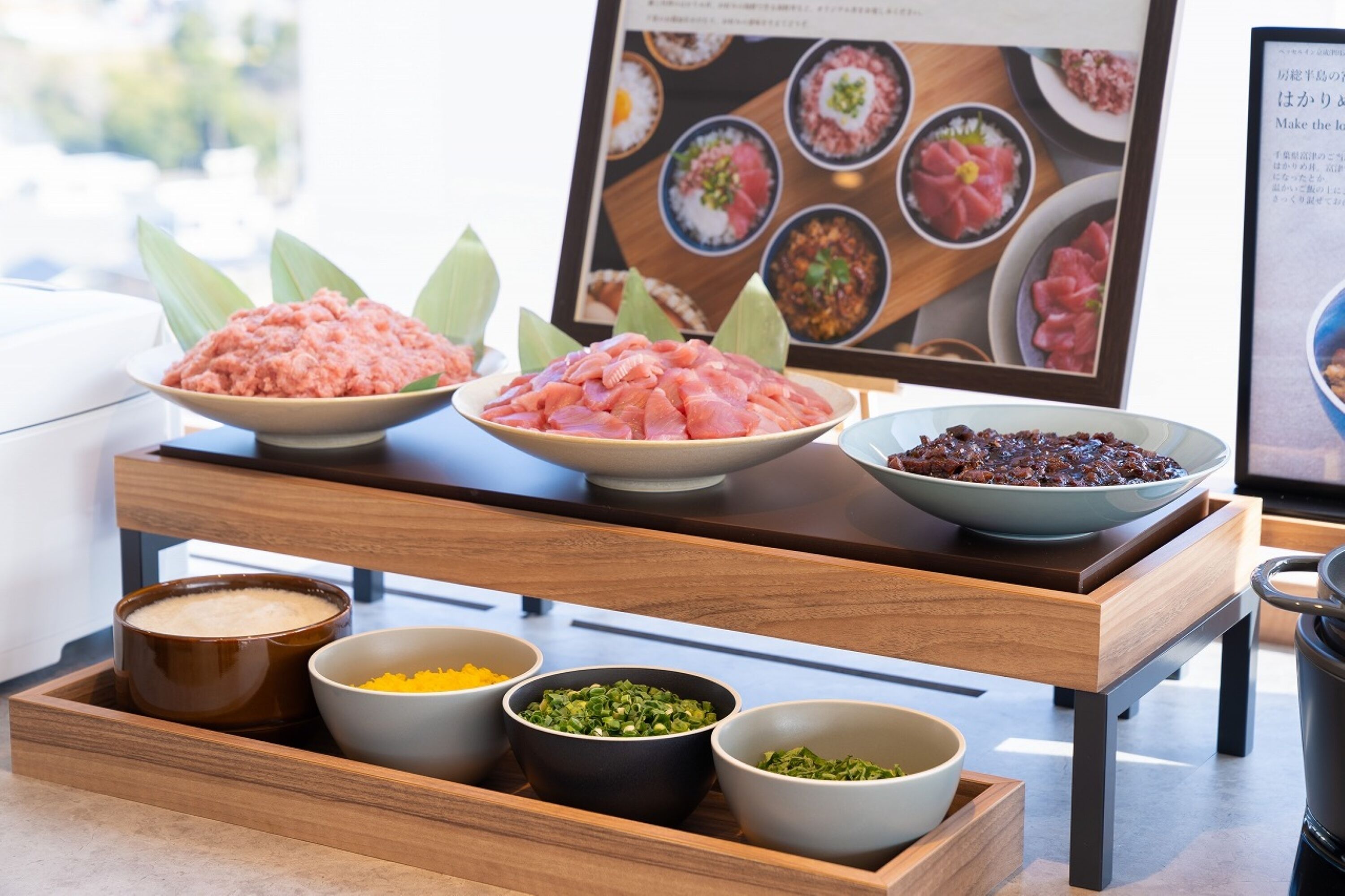 Een buffetopstelling met diverse gerechten, waaronder een schaal rauwe vis, een schaal rode bonen en verschillende kleine schaaltjes met toevoegingen.