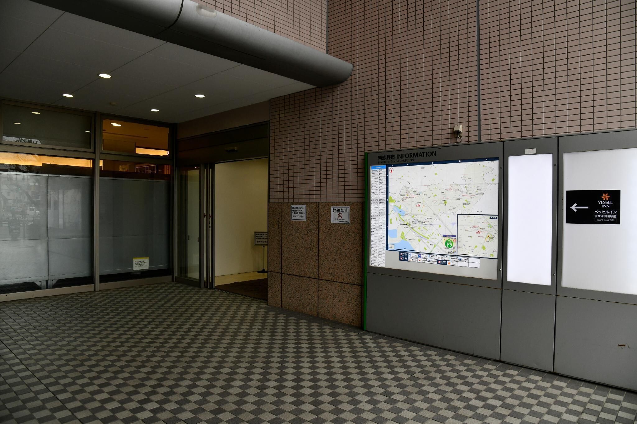 A tiled floor with a checkered pattern, a map display, and a sign indicating a no-smoking area.