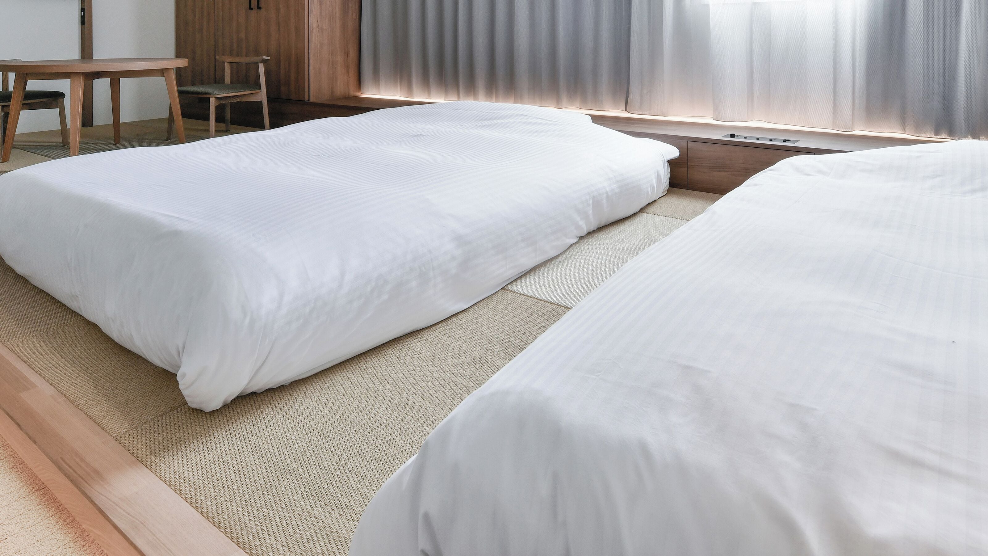 Une chambre d’hôtel avec deux lits, une table en bois et une chaise.
