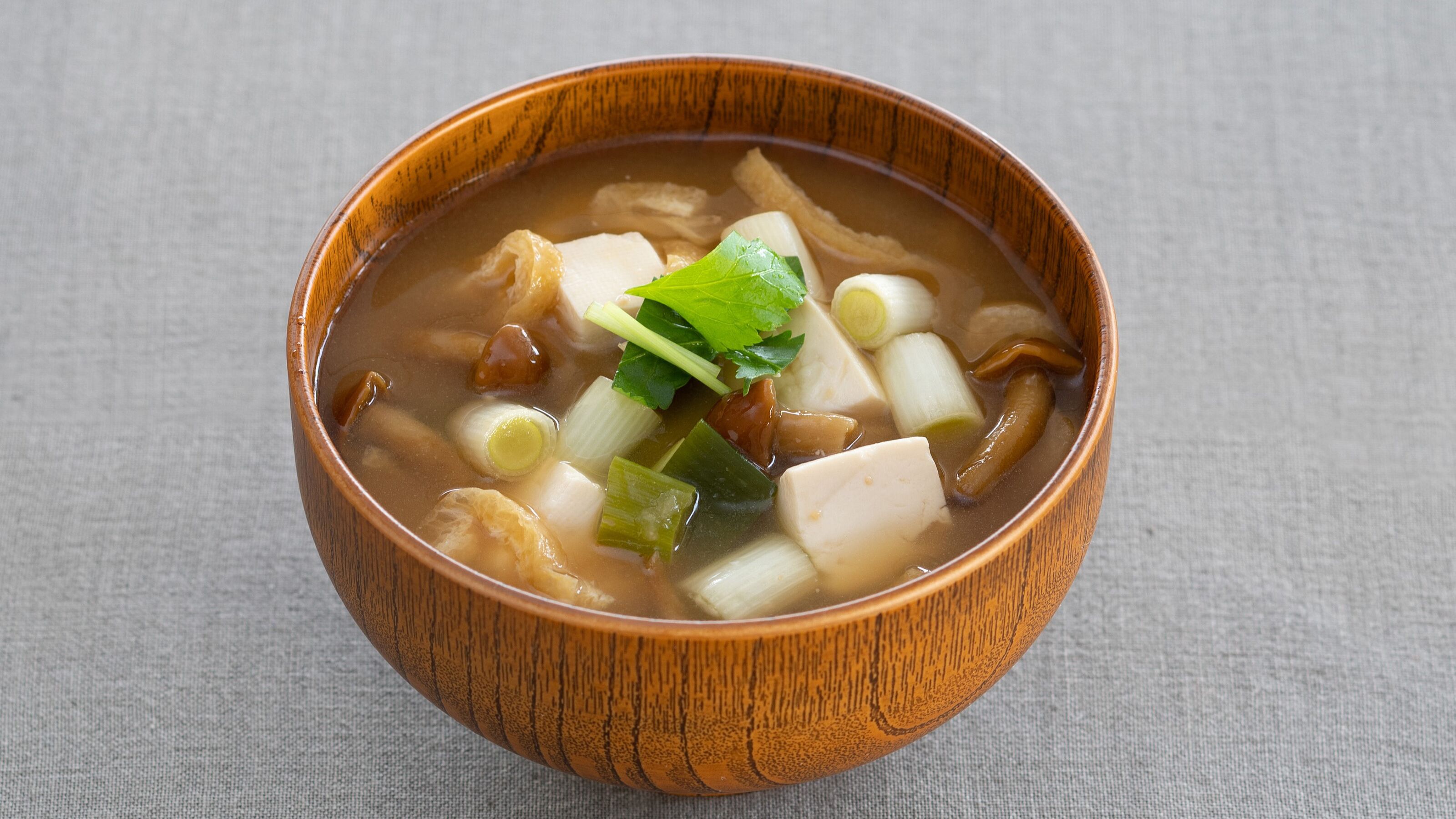 A bowl of soup with tofu and vegetables.