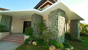 A modern building with a stone facade, a covered entrance, and a well-maintained garden.