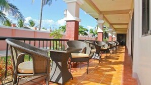 A covered outdoor seating area with wicker furniture and a tiled floor.