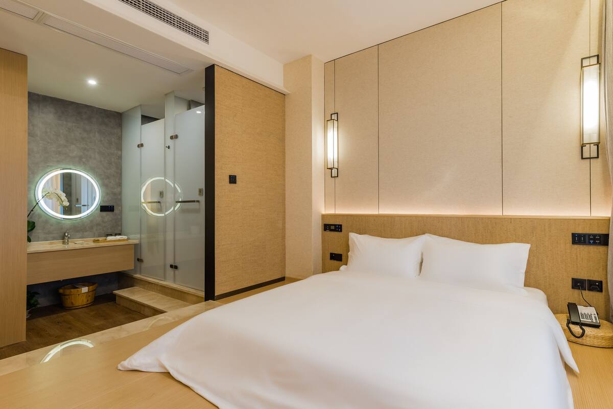 A hotel room with a large bed, a vanity with a mirror, and a walk-in closet.