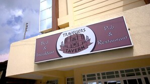 A sign for 'Travelers Tavern' indicating it offers bed & breakfast and a pub & restaurant. - Travellers Tavern (Nkubu)