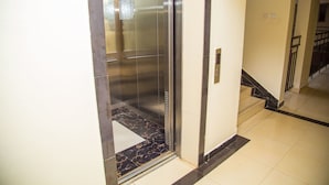 An elevator with a metallic interior, a tiled floor, and a wall-mounted control panel. - Nairobi Luxury Suites (Nairobi)