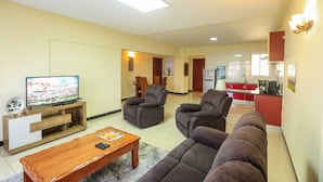 A living room with a flat-screen TV, two grey sofas, a wooden coffee table, and a small TV stand. - Nairobi Luxury Suites (Nairobi)